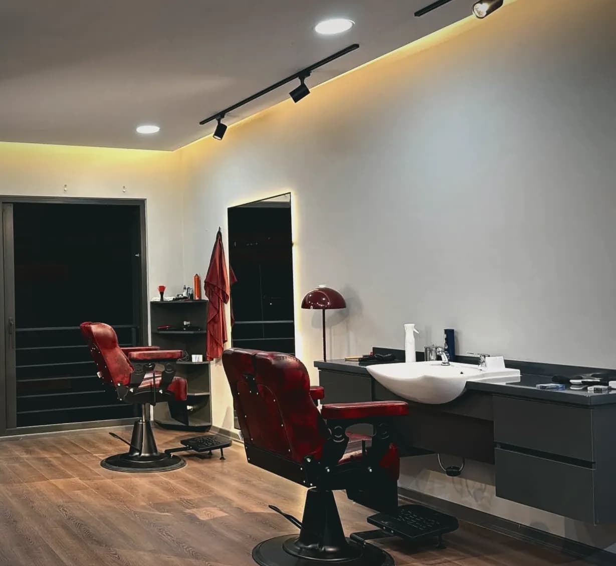 Rain Barber Studio'nun çalışma alanı: bordo deri berber koltukları ve ray spotlar