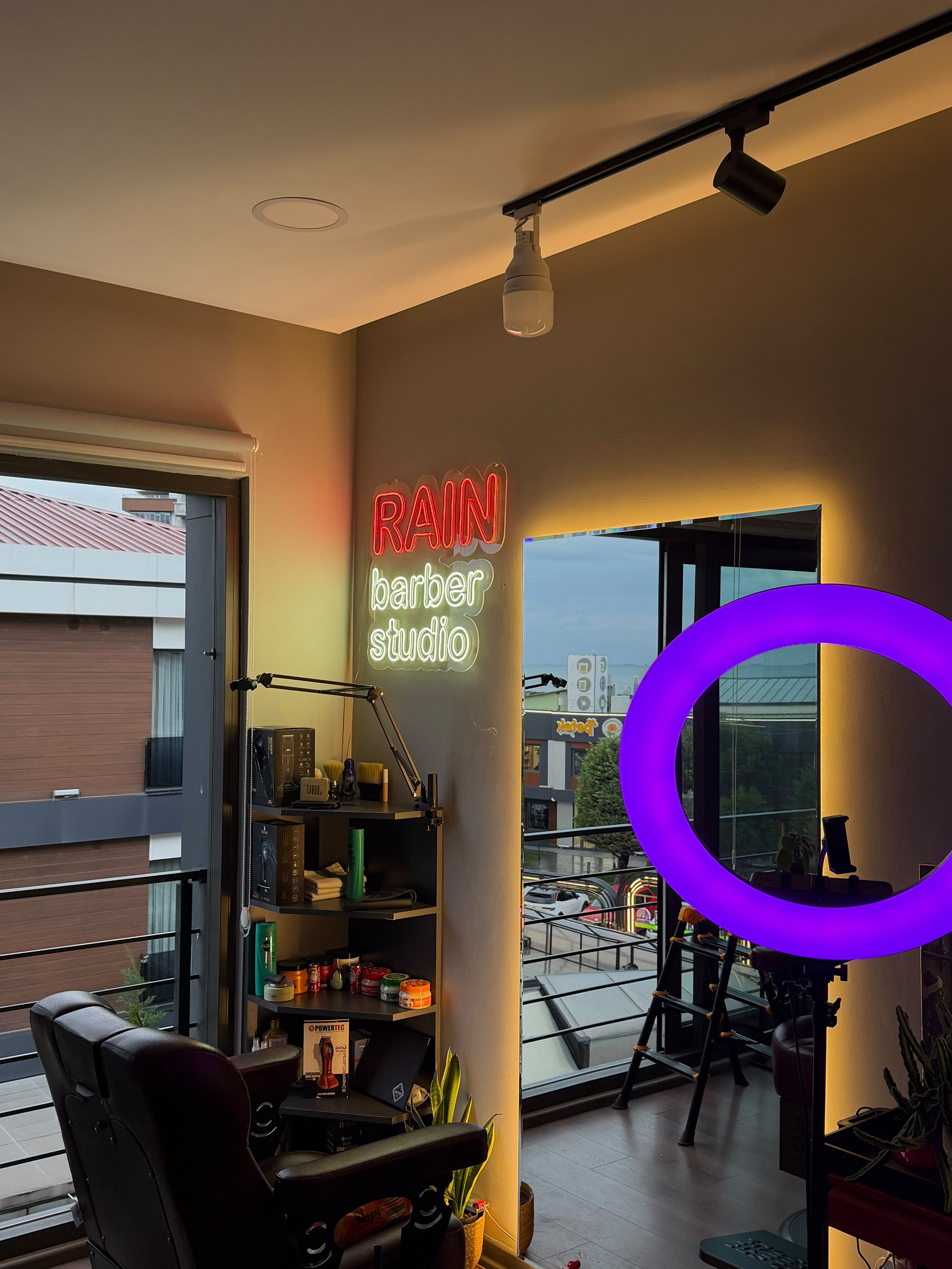 Rain Barber Studio neon tabelası, ayna ve kesim istasyonu